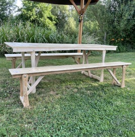 Ensemble table et bancs pliants en bois massif sous une tonnelle artisanale. Mobilier de jardin robuste et élégant, conçu pour les repas conviviaux en extérieur.