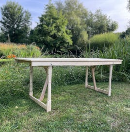 Table pliante artisanale en bois massif, vue en perspective. Un design sobre et fonctionnel, idéal pour les repas de groupe en intérieur ou extérieur.